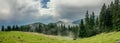 Epic mountain scenery with blue sky and pine trees and mist