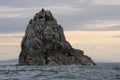 Epic seascape. Small figures of people are visible on a huge rock in the sea. Royalty Free Stock Photo