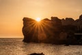 An epic sunset on the sea - the sun sets behind the mountain and everything shines with warm light with long rays.