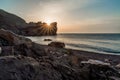 An epic sunset on the sea - the sun sets behind the mountain and everything shines with warm light with long rays.