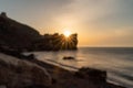 An epic sunset on the sea - the sun sets behind the mountain and everything shines with warm light with long rays.