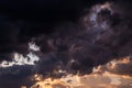 Epic sunset storm sky. Big dark grey cumulus thunderstorm clouds in yellow orange sunlight Royalty Free Stock Photo