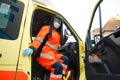 Epic superhero shot: Serious female paramedic sits at ambulance vehicle ready for action