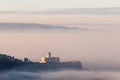 An epic view of St.Francis church in Assisi town Umbria above a sea of fog at dawn