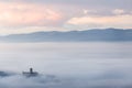 An epic view of St.Francis church in Assisi town Umbria above a sea of fog at dawn