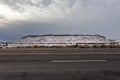 Epic wide angle shot of snow covered mesa plateau along empty highway in rural New Mexico