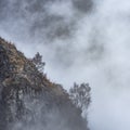 Epic Winter landscape image of view from Side Pike towards Langdale pikes with low level clouds on mountain tops and moody mist Royalty Free Stock Photo