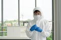 Epidemiological researchers in virus protective clothing carefully looking at chemical in glass bottle. Coronavirus disease 2019