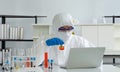 Epidemiological researchers in virus protective clothing mixing chemicals according to formulas obtained from computers. Working