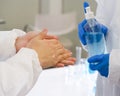 Epidemiological researchers in virus protective clothing washing hands with alcohol gel before beginning the experiment in a