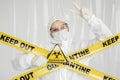Epidemiologist woman in protective clothing is in a restricted area with a danger sign. Yellow line Keep Out Quarantine Royalty Free Stock Photo