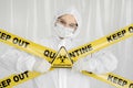 Epidemiologist woman in protective clothing is in a restricted area with a danger sign. Yellow line Keep Out Quarantine Royalty Free Stock Photo