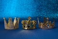 Epiphany Day or Dia de Reyes Magos concept. Three gold crowns on blue sparkling background