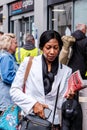 Black Woman Walking In A Crowd Carrying Newspaper