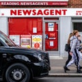 Group Of young People Walking Past A Traditional Newsagent Paper Shop Or Store