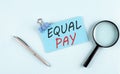 EQUAL PAY text written on a sticky with magnifier and pen, business concept Royalty Free Stock Photo