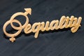 EQUALITY word carved out of plywood. Symbol of gender equality. Black wooden background