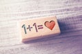 Equation 1 plus 1 equals Heart As A Love Concept Engraved On A Wooden Block On A Table Royalty Free Stock Photo