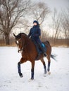 Equestrian country girl riding her bay horse in winter Royalty Free Stock Photo