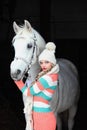 Equestrian girl with her white horse in stable door at winter morning Royalty Free Stock Photo