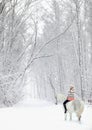Equestrian girl riding her andalusian horse through snow at winter morning Royalty Free Stock Photo