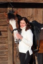 Equestrian girl with a saddle horse in winter stable