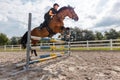 Equestrienne exercising hurdle jump in an outdoor riding arena