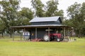 Equipment for agriculture and recreation sits under the shed roof of a painted wooden barn in a pecan orchard in rural Georgia