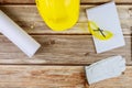 Equipment of construction blueprints, safety helmet and goggles with notebook on wood table