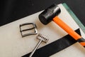 Equipment for genuine leather belt production on the table in the workshop. Genuine leather belt, buckle, hammer and Royalty Free Stock Photo