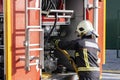 Equipped firefighter handling a water extraction pump, inside a fire truck