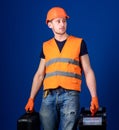 Equipped repairman concept. Man in helmet, hard hat holds toolbox and suitcase with tools, blue background. Worker Royalty Free Stock Photo