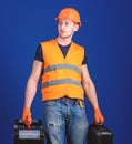Equipped repairman concept. Man in helmet, hard hat holds toolbox and suitcase with tools, blue background. Worker Royalty Free Stock Photo