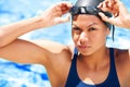 Equipped to win. Determined young female swimmer adjusting her swimming goggles.