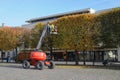 Equipped worker pruning a tree on a crane. Gardening