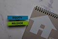 Equity Release write on sticky note and house made from paper isolated on Office Desk. Retirement concept