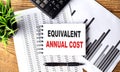 EQUIVALENT ANNUAL COST text on a notebook with chart and calculator