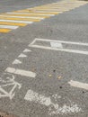 An almost erased bike lane sign on an asphalt road next to a pedestrian crossing Royalty Free Stock Photo