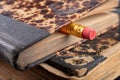 Eraser bound on a pencil and an old book. Writing accessories and books on an old table Royalty Free Stock Photo