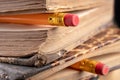 Eraser bound on a pencil and an old book. Writing accessories and books on an old table Royalty Free Stock Photo