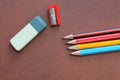 eraser, writing pencils and a sharpener on a brown leather background