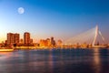 Erasmus bridge over the river Meuse with skyscrapers and moon in Rotterdam, South Holland, Netherlands during twilight sunset.