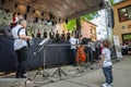 ERDEVIK, SERBIA - JUNE 3, 2023: toddler observing musicians and a group of children, boys & girls dancing a Serbian kolo in Royalty Free Stock Photo