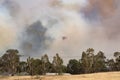 Erickson Air Crane helicopter N243AC Sikorsky S-64 flying against plumes of smoke while fighting bush fires in Victoria. Royalty Free Stock Photo