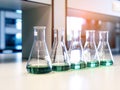 The Erlenmeyer or Conical flasks on bench laboratory, with range of green solvent forming reaction between boric acid and ammonia. Royalty Free Stock Photo