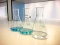 Erlenmeyer flasks on bench in chemistry laboratory with blue solvent indicator, titration water sample. Royalty Free Stock Photo
