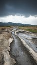 Eroded road winding through an abandoned rural landscape beneath a dramatic overcast sky Royalty Free Stock Photo