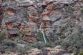 Sandstone cliff with ephemeral waterfall, desert varnish and green moss