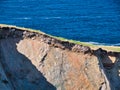 Eroding soil, subsoil and bedrock shown on sheer cliffs near Uyea in Northmavine, Shetland, UK.