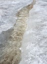 Erosion from flood waters. Spring stream. Snow washed away by a stream. Vertical view